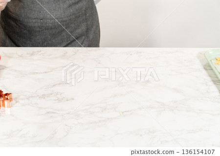 A close up from a wifes perspective of a cookie cutter and sugar cookie dough prepared for shaping 136154107