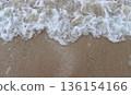 Foam and water spreading on beach sand 136154166