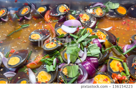 Authentic Thai spicy century egg salad with chili, onions, and herbs. A delicious and colorful traditional Thai appetizer featuring preserved black eggs with savory flavors 136154223