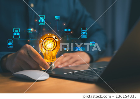 Businessman holding glowing light bulb with target icon and laptop, symbolizing innovation, business strategy, digital marketing ideas for startup growth, franchise, or business expansion in 2026. Businessman holding glowing light bulb with target icon and laptop, symbolizing innovation, business strategy, digital marketing ideas for startup growth, franchise, or business expansion in 2026. 136154335