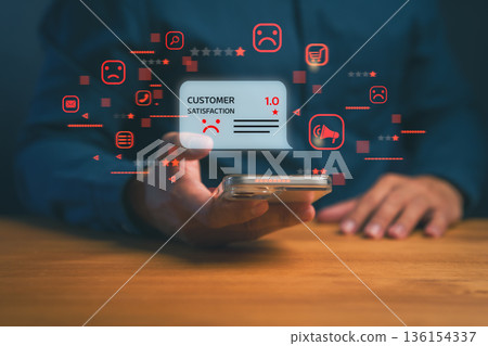 Customer holding smartphone showing one-star negative review and sad face icon, representing poor service, bad experience, and low satisfaction in online business or digital feedback concept. 136154337