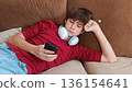 Close-up view of a teen boy lying on a couch and answering his cell phone. a guy is lying on the couch using his phone 136154641