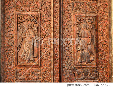 ROMANIA, Bucharest, Old Town Center - January 8, 2019: Old Church Door With Saints sculpted in the wood. Stavropoleos Monastery situated downtown on Lipscani Street was built in 1724. The name ROMANIA, Bucharest, Old Town Center - January 8, 2019: Old Church Door With Saints sculpted in the wood. Stavropoleos Monastery situated downtown on Lipscani Street was built in 1724. The name 136154679