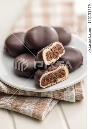 Dark chocolate truffles in the shape of coffee beans on plate on white table. 136155279