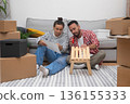 Crafting Home Together: A happy couple in a new apartment builds a modern wooden shelf unit surrounded by boxes, enhancing their home decor during the move 136155333