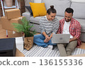 Designing Dreams: Young homeowners or renters in a new apartment, laptop amidst boxes, shape their ideal living space, shop online, or manage their move 136155336