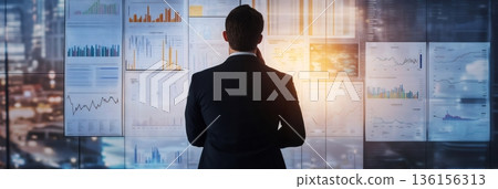 Businessman in a suit stands before a wall filled with charts and graphs, focusing on financial data analysis. The scene conveys multitasking, time management, and work stress Businessman in a suit stands before a wall filled with charts and graphs, focusing on financial data analysis. The scene conveys multitasking, time management, and work stress 136156313