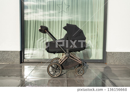 Modern baby stroller standing near large window. Minimal family lifestyle and parenting concept. 136156668