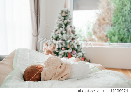 Newborn baby sleeping in cozy bedroom with Christmas tree. Family holiday, winter, Christmas lifestyle concept Newborn baby sleeping in cozy bedroom with Christmas tree. Family holiday, winter, Christmas lifestyle concept 136156674