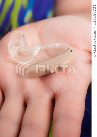 senior person holding hearing aid closeup senior person holding hearing aid closeup 136156721