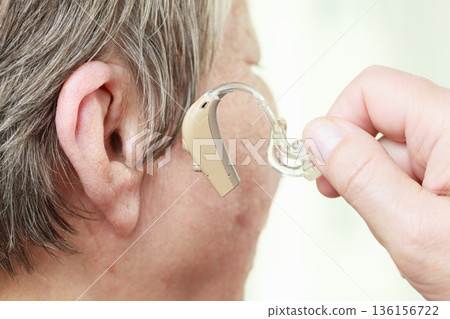 Closeup senior woman using hearing aid 136156722