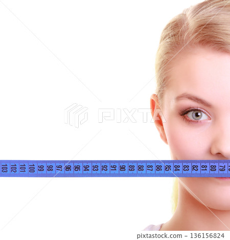Fitness girl fit woman covering her mouth with measuring tape Fitness girl fit woman covering her mouth with measuring tape 136156824