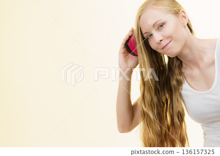 Blonde girl brushing her long hair 136157325