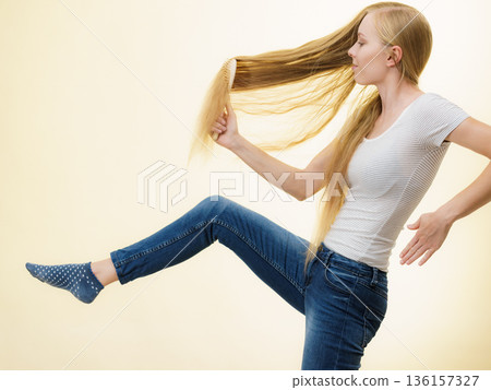 Blonde girl brushing her long hair 136157327