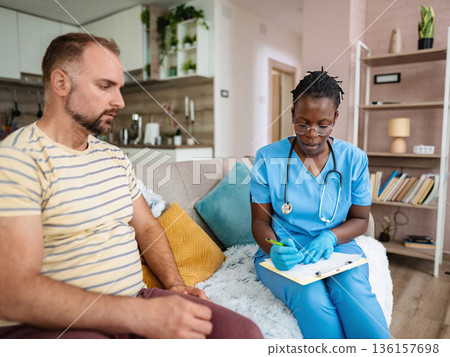 Nurse engages with patient in a cozy home setting Nurse engages with patient in a cozy home setting 136157698