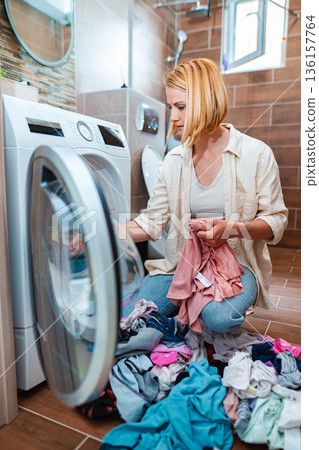 Laundry day: Sorting clothes in a modern laundry room Laundry day: Sorting clothes in a modern laundry room 136157764