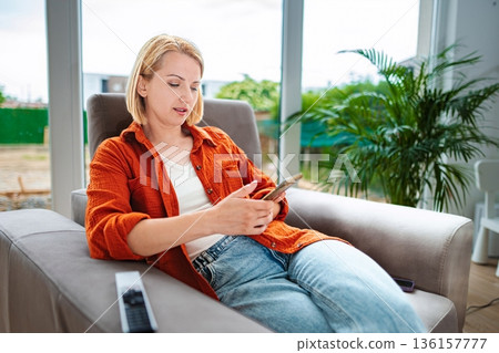 Relaxing moment at home while browsing on the phone Relaxing moment at home while browsing on the phone 136157777
