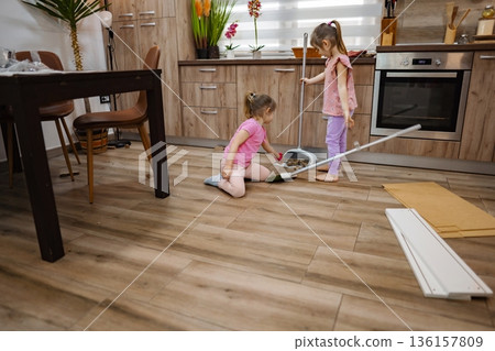 Two children joyfully cleaning the kitchen on a sunny afternoon Two children joyfully cleaning the kitchen on a sunny afternoon 136157809