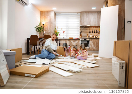 Family enjoying quality time assembling furniture in a cozy kitchen 136157835