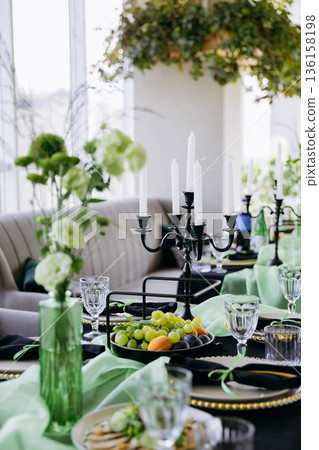 Luxury green and black dinner table setting with candles, flowers and glassware Luxury green and black dinner table setting with candles, flowers and glassware 136158198
