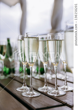 Champagne flutes with sparkling wine on wooden table, festive celebration Champagne flutes with sparkling wine on wooden table, festive celebration 136158201