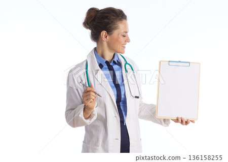 Healthcare Professional Holding Clipboard Looking Aside Healthcare Professional Holding Clipboard Looking Aside 136158255