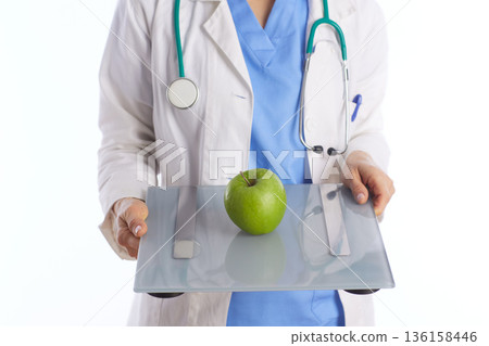 Medical Professional Holding Weight Scale with Green Apple 136158446