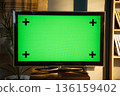 Television with bright green chroma key screen and black tracking markers on a wooden surface in a modern living room, ideal mockup for video, vfx and advertising templates 136159402