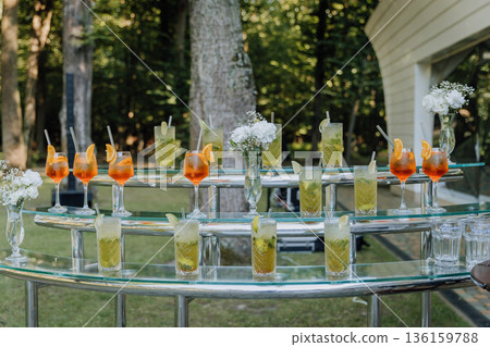 Outdoor cocktail bar setup with aperol spritz and mojito drinks on serving station, summer event 136159788