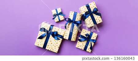 Top view Christmas present box with blue bow on purple background Top view Christmas present box with blue bow on purple background 136160043