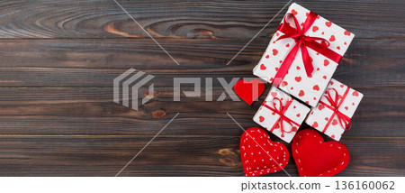 Valentine or other holiday handmade present in paper with red hearts and gifts box in holiday wrapper. Present box of gift on Dark wooden table top view with copy space, empty space for design 136160062