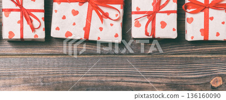 valentine or other holidays concept. Lots of Gift boxes on wood background top view. Presents in craft paper decorated with red ribbon bows and heart. Top view frame with copy space 136160090