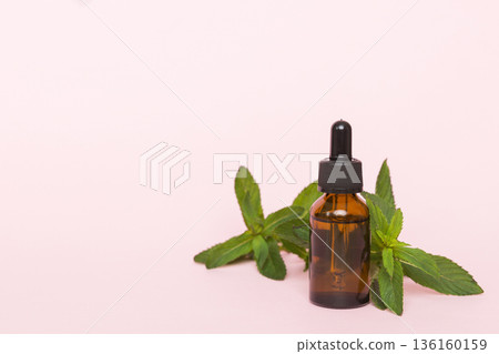 Natural Mint Essential Oil in a Glass Bottle. organic cosmetics with herbal extracts of mint on colored background 136160159
