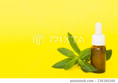 Natural Mint Essential Oil in a Glass Bottle. organic cosmetics with herbal extracts of mint on colored background 136160160