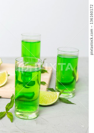 Sweet refreshing mint liqueur, with ice and mint leaves on table background, Shots with lime slice and mint flat lay Sweet refreshing mint liqueur, with ice and mint leaves on table background, Shots with lime slice and mint flat lay 136160172