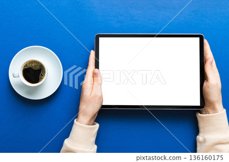 Close up image woman hands holding digital tablet with blank copy space screen for your text message or promotional content om table with cup of coffee. hands of a woman holding blank tablet device Close up image woman hands holding digital tablet with blank copy space screen for your text message or promotional content om table with cup of coffee. hands of a woman holding blank tablet device 136160175