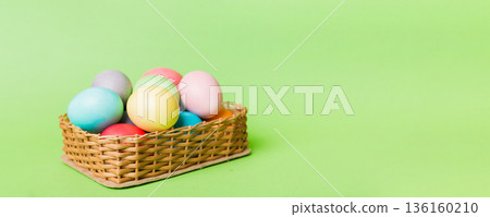 Multi colors Easter eggs in the woven basket on colored background . Pastel color Easter eggs. holiday concept with copy space Multi colors Easter eggs in the woven basket on colored background . Pastel color Easter eggs. holiday concept with copy space 136160210