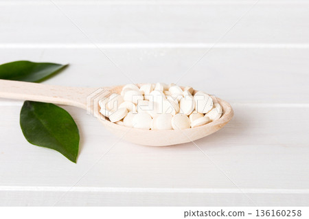 Heap of white pills on colored background. Tablets scattered on a table. Pile of red soft gelatin capsule. Vitamins and dietary supplements concept Heap of white pills on colored background. Tablets scattered on a table. Pile of red soft gelatin capsule. Vitamins and dietary supplements concept 136160258