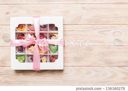 Box with sweet chocolate candies on color background, Various candy sweets. Valentines day gift box. Top view flat lay with copy space Box with sweet chocolate candies on color background, Various candy sweets. Valentines day gift box. Top view flat lay with copy space 136160278