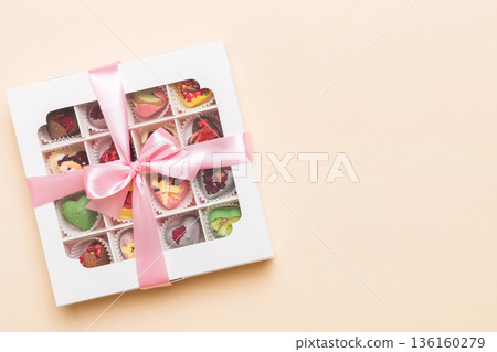 Box with sweet chocolate candies on color background, Various candy sweets. Valentines day gift box. Top view flat lay with copy space Box with sweet chocolate candies on color background, Various candy sweets. Valentines day gift box. Top view flat lay with copy space 136160279