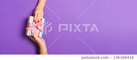 Top view of a woman and a man giving and receiving a present on colorful background. Love and relationship concept. Close up Top view of a woman and a man giving and receiving a present on colorful background. Love and relationship concept. Close up 136160416