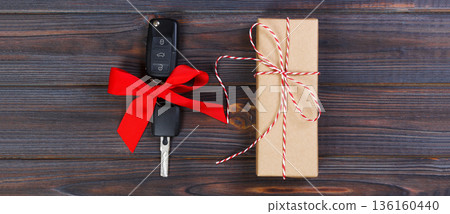 Close-up view of car keys with red bow as present on wooden background Close-up view of car keys with red bow as present on wooden background 136160440