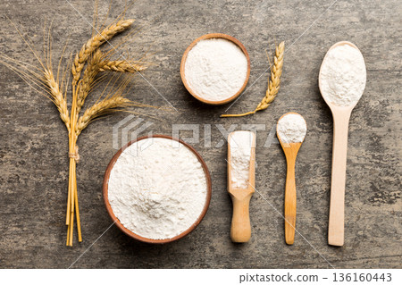 Flat lay of Wheat flour in wooden bowl with wheat spikelets on colored background. world wheat crisis Flat lay of Wheat flour in wooden bowl with wheat spikelets on colored background. world wheat crisis 136160443