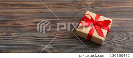 Wrapped christmas or other holiday handmade present in craft paper with colored ribbon. Present box, decoration of gift on table, top view with copy space 136160482
