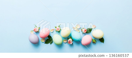 Happy Easter. Easter eggs on colored table with yellow roses. Natural dyed colorful eggs background top view with copy space Happy Easter. Easter eggs on colored table with yellow roses. Natural dyed colorful eggs background top view with copy space 136160537