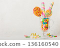 Colorful candies in cup on table on light background background. Large swirled lollipops. Creative concept of a jar full of delicious sweets from the candy store 136160540
