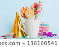 Colorful candies in cup on table on light background background. Large swirled lollipops. Creative concept of a jar full of delicious sweets from the candy store 136160541