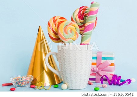 Colorful candies in cup on table on light background background. Large swirled lollipops. Creative concept of a jar full of delicious sweets from the candy store 136160541