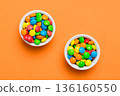 Multicolored candies in a bowl on a colored background. birthday and holiday concept. Top view with copy space 136160550