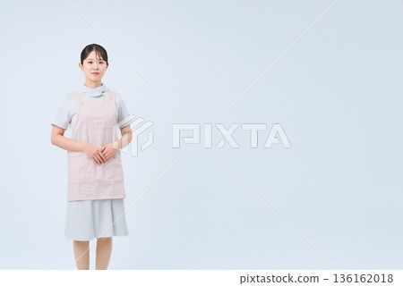 A young woman wearing a white coat and apron A young woman wearing a white coat and apron 136162018